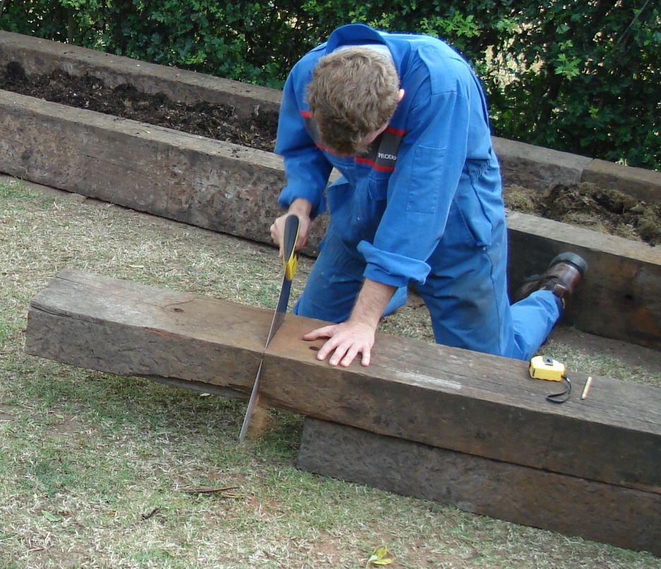 Cutting railway sleepers by hand with a handsaw. Railwaysleepers.com
