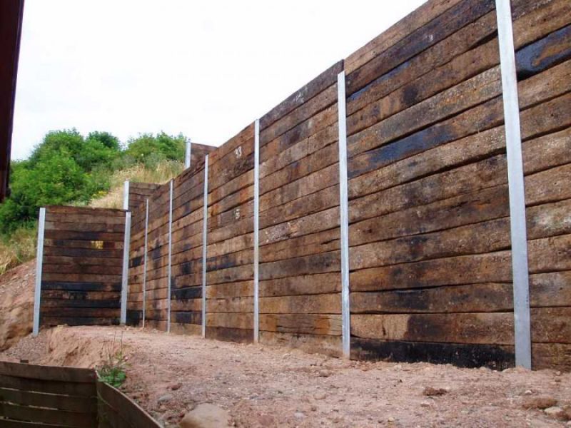Huge height of wall possible with old railway sleepers slotted into vertical steel H beams. Railwaysleepers.com 